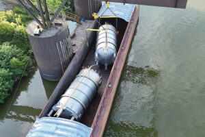 Indiana River & Rail Terminals staff (note the orange shirt next to the top tank and the green-vested employee on the dock) prepare to lift a 51-ton pharmaceutical-production tank from a barge at Ports of Indiana-Mount Vernon on the Ohio River.