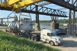 A truck driver prepares for departure from Ports of Indiana-Mount Vernon while Indiana River & Rail Terminals crews complete transload of this 51-ton, 44-by-18-foot pharmaceutical production tank from a barge on the Ohio River.